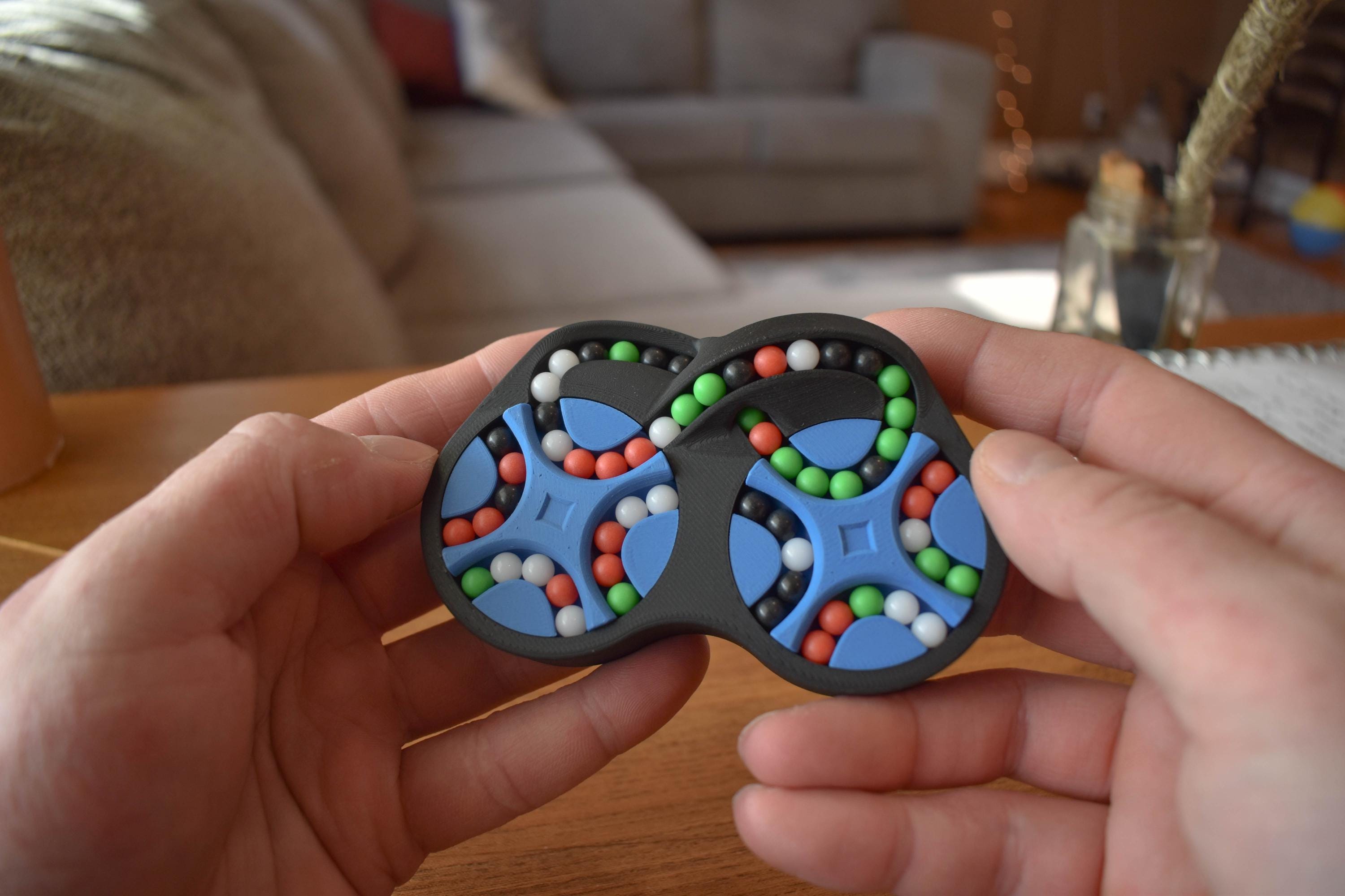 Compact mechanical puzzle with four interconnected colored rings featuring small colorful beads for brainteaser and fidget. - andEleven - The Figure-Eight (4-Color)