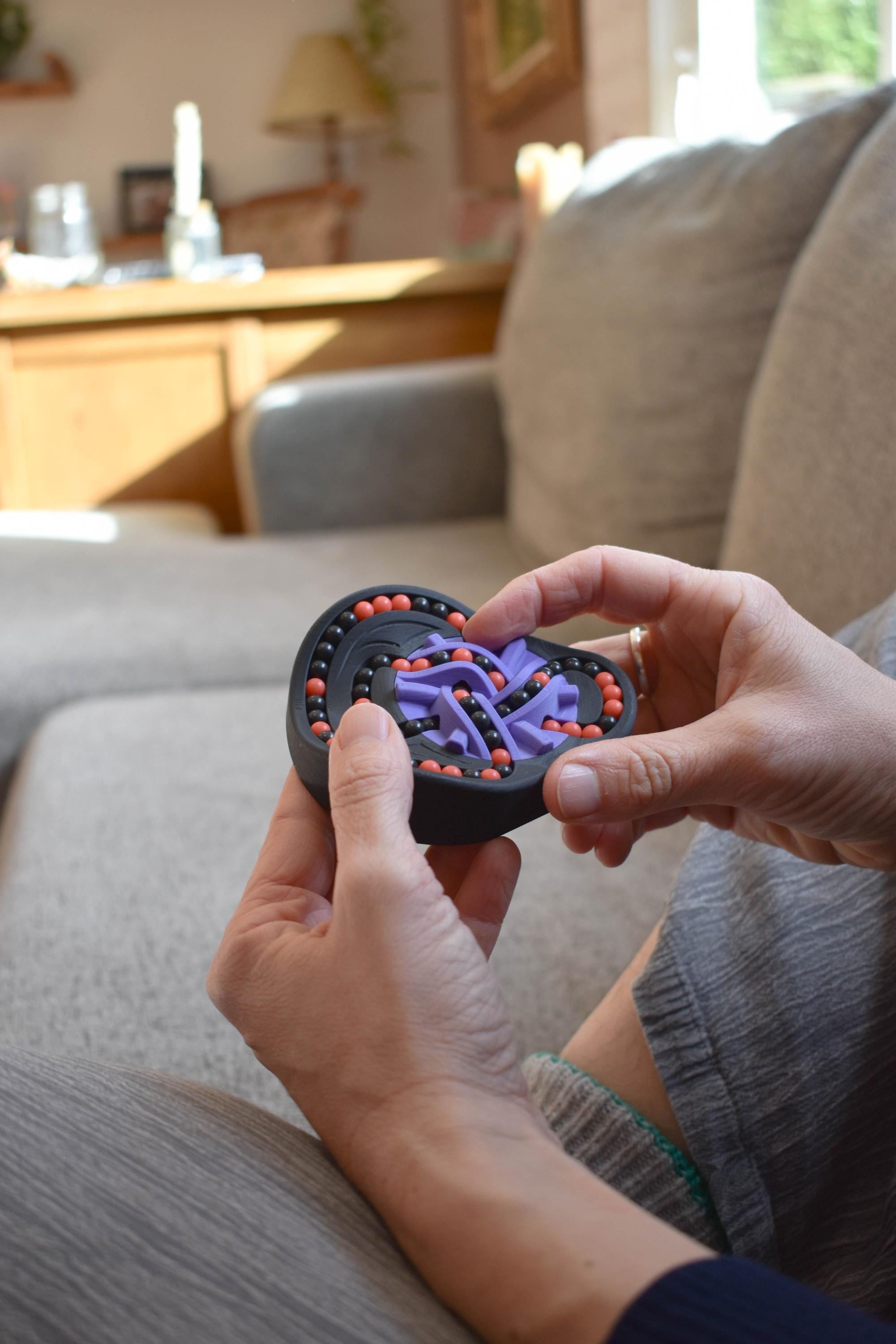Black and purple heart-shaped mechanical puzzle held as a brainteaser fidget toy. - andEleven - The Taurus (2-Color)