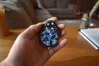 Compact black mechanical puzzle with blue tracks and silver balls, designed as a brainteaser fidget toy. - andEleven - The Pretzel