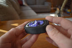 Compact black and purple mechanical puzzle brainteaser fidget held between hands on wooden table. - andEleven - The Infinity (2-Color)
