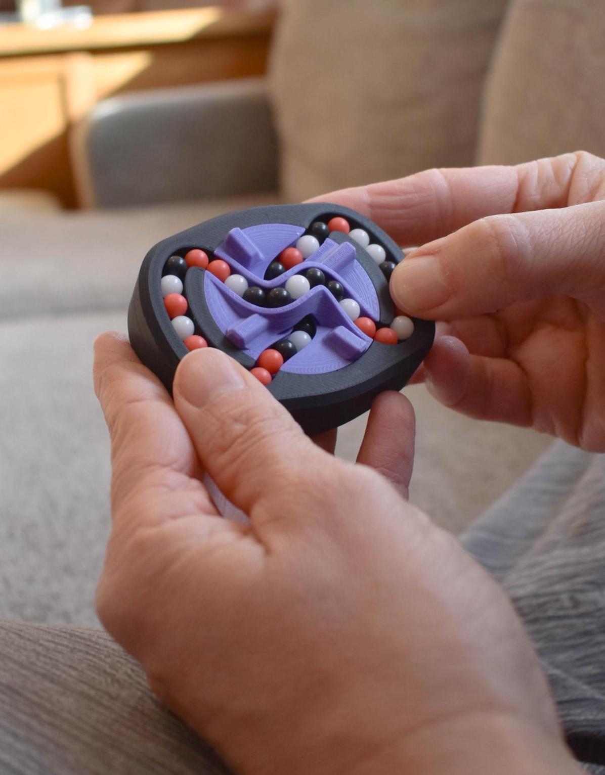 Compact mechanical puzzle with three-color purple, black, and red design held as a brainteaser fidget toy. - andEleven - The Infinity (3-Color)