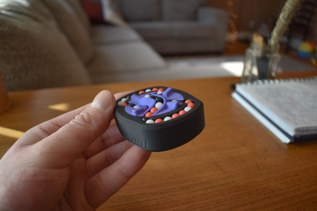 Black round mechanical puzzle with colorful bead brainteaser held in hand, designed for fidgeting. - andEleven - The Infinity (3-Color)
