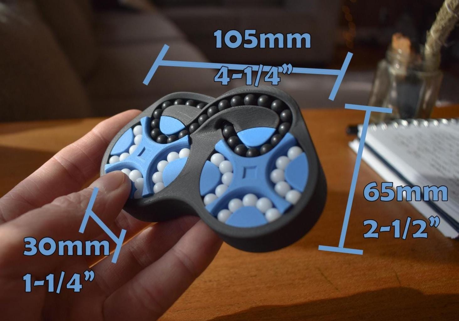 Two-color mechanical puzzle brainteaser fidget in figure-eight shape with blue and black parts, held in hand. - andEleven - The Figure-Eight (2-Color)