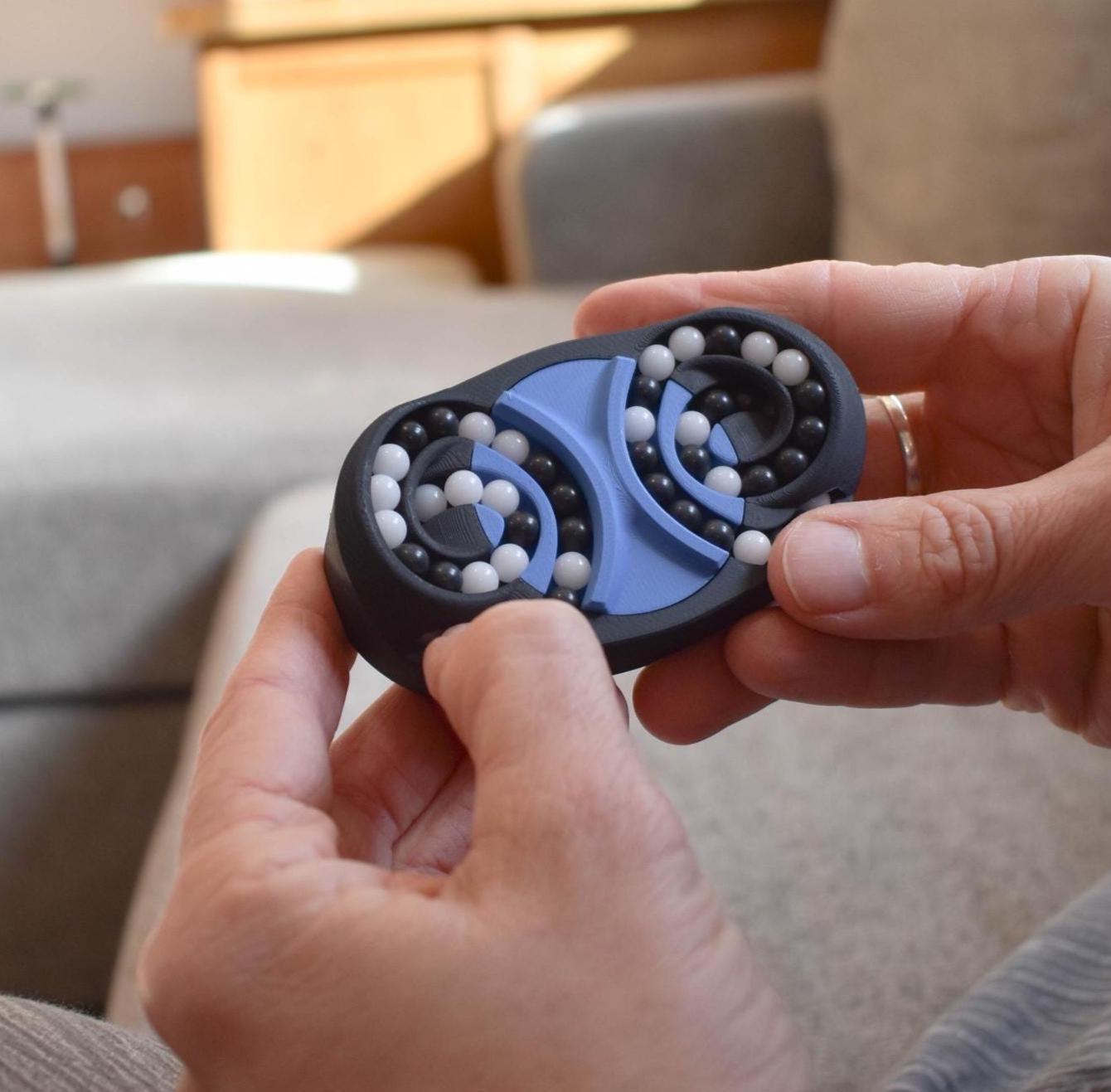 Blue and black butterfly-shaped mechanical puzzle brainteaser fidget with rotating beads held in hands. - andEleven - The Butterfly