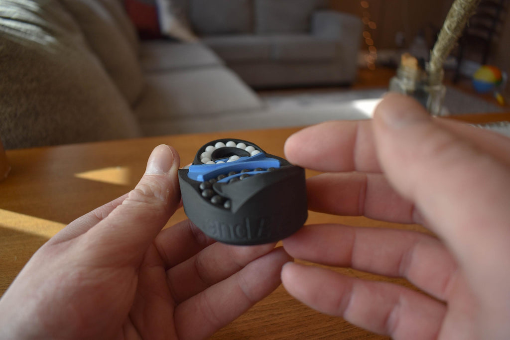 Black and blue mechanical puzzle held in hands, brainteaser and fidget toy with interlocking pieces. - andEleven - The Butterfly