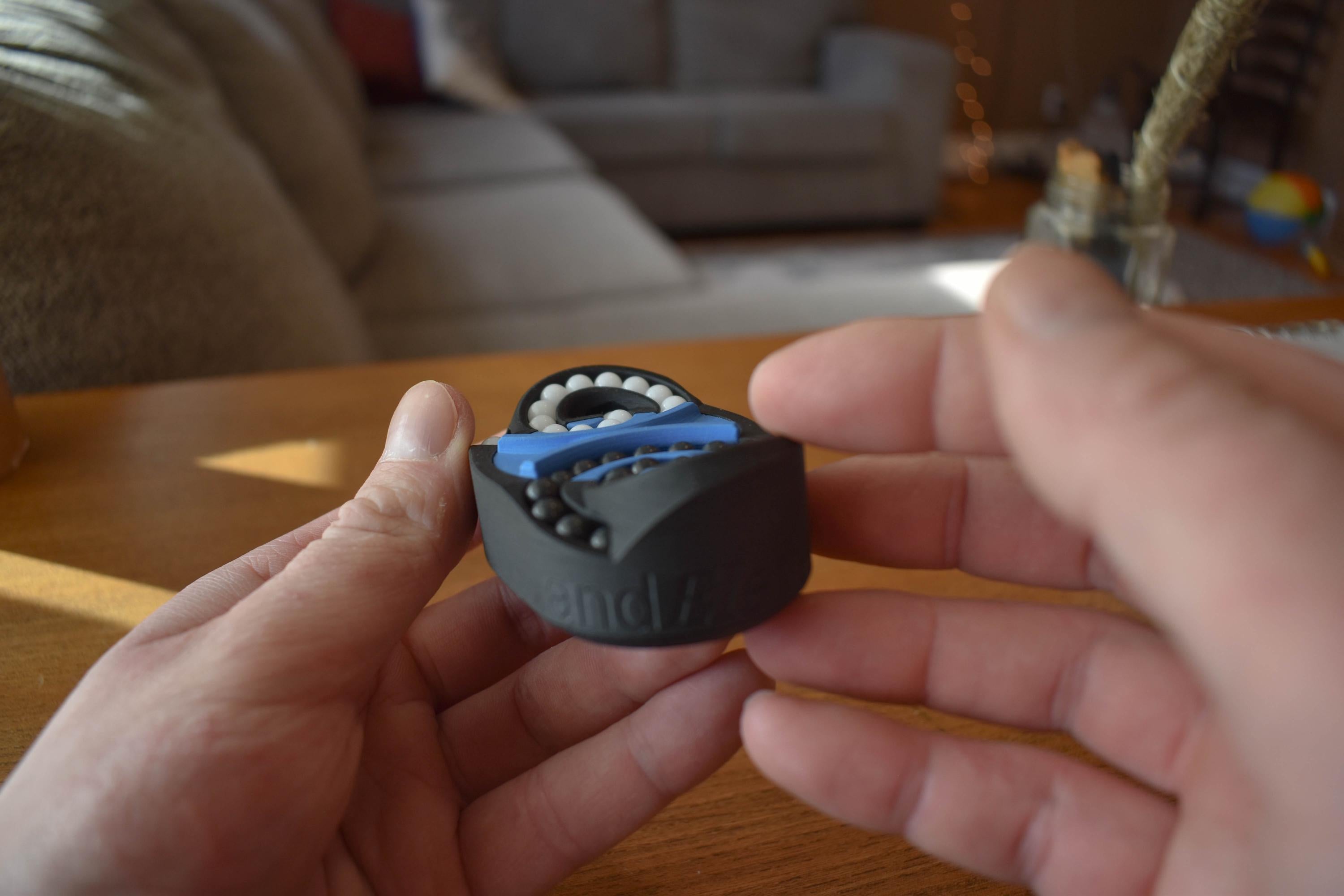 Black and blue mechanical puzzle held in hands, brainteaser and fidget toy with interlocking pieces. - andEleven - The Butterfly