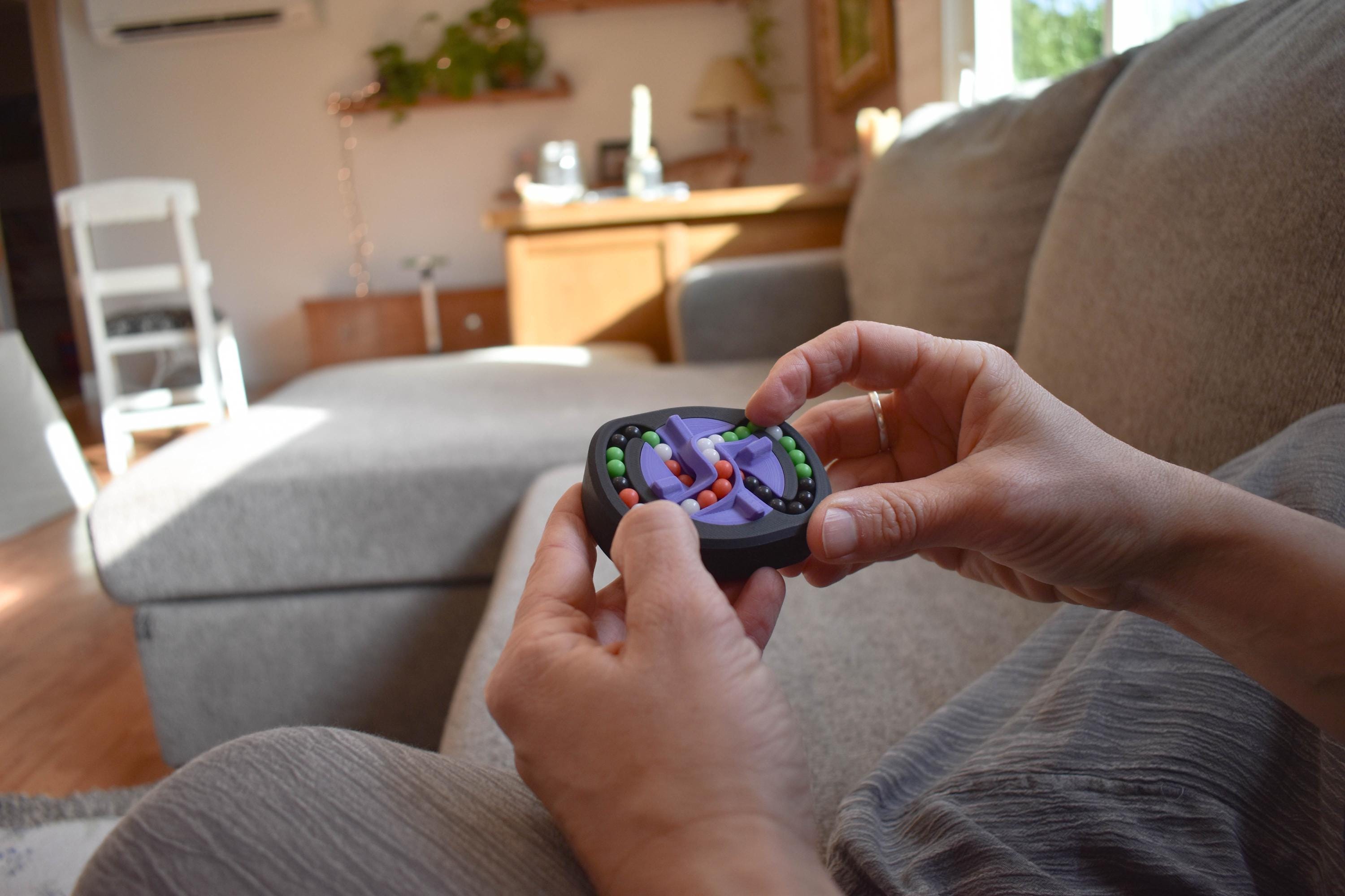 Compact black mechanical puzzle with colorful rotating pieces held as a brainteaser fidget toy. - andEleven - The Infinity (4-Color)