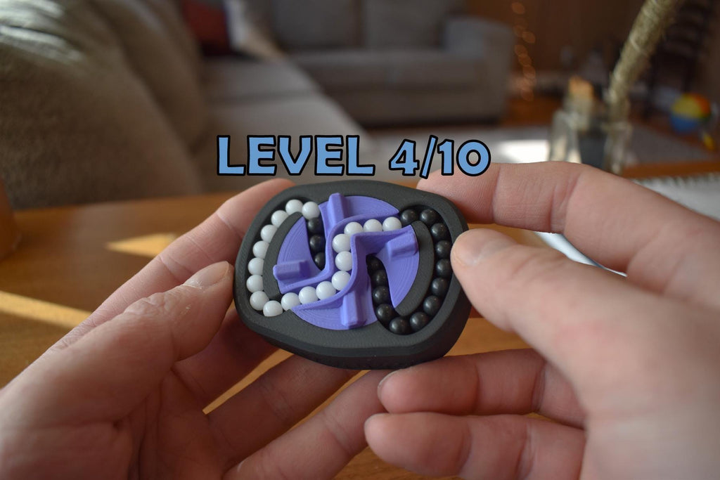 Small black and purple mechanical puzzle brainteaser fidget held in hands with visible level 4/10 indicator. - andEleven - The Infinity (2-Color)