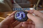 Small black and purple mechanical puzzle brainteaser fidget held in hands with visible level 4/10 indicator. - andEleven - The Infinity (2-Color)