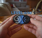 Compact blue and black mechanical puzzle brainteaser held in hands, featuring rotating bead tracks for fidgeting. - andEleven - The Butterfly