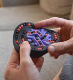 The Taurus 2-color mechanical puzzle with black base, purple intertwined loops, and red beads held in hands, interactive. - andEleven - The Taurus (2-Color)