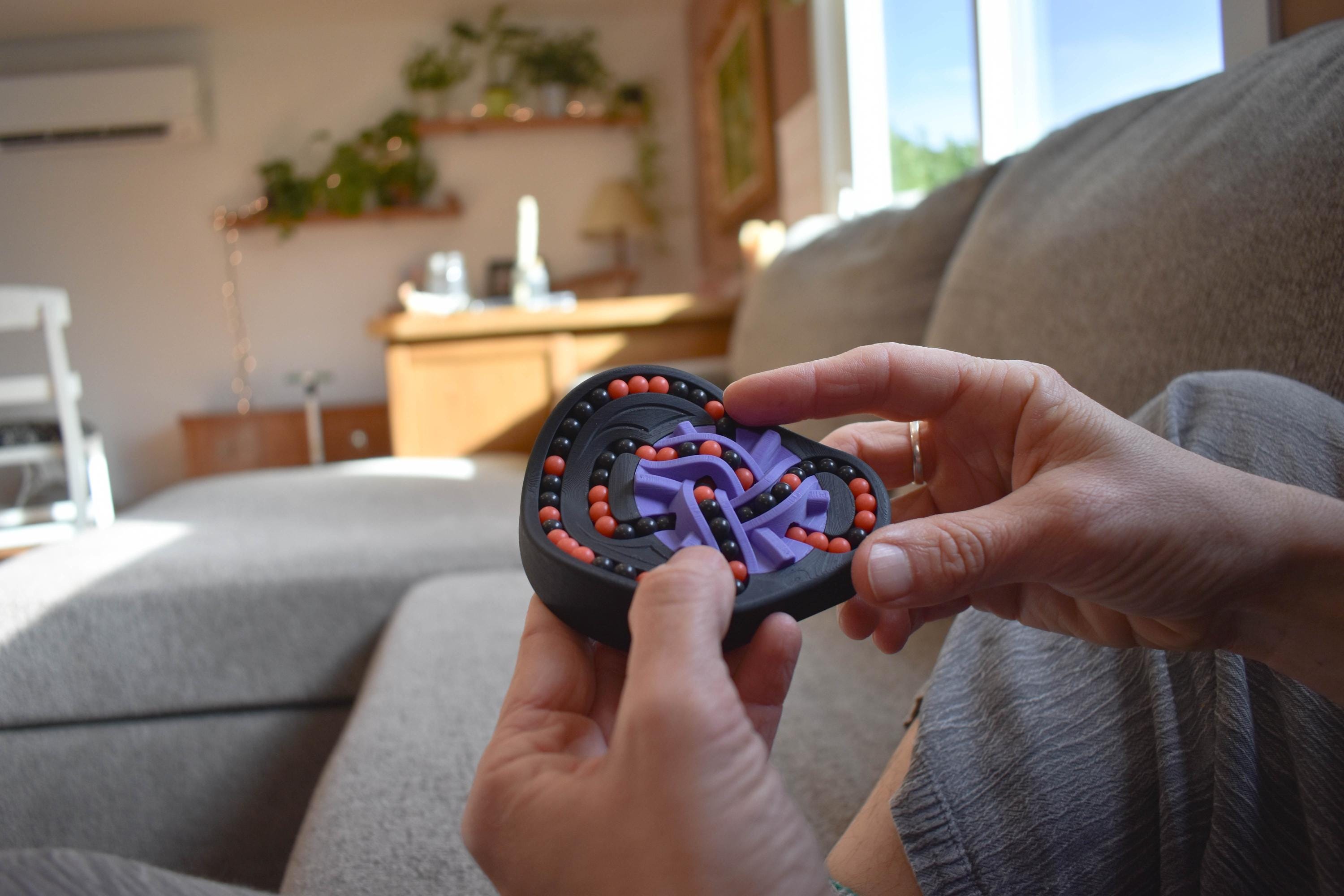 Hands holding The Taurus mechanical puzzle in black and purple, a brainteaser fidget toy. - andEleven - The Taurus (2-Color)