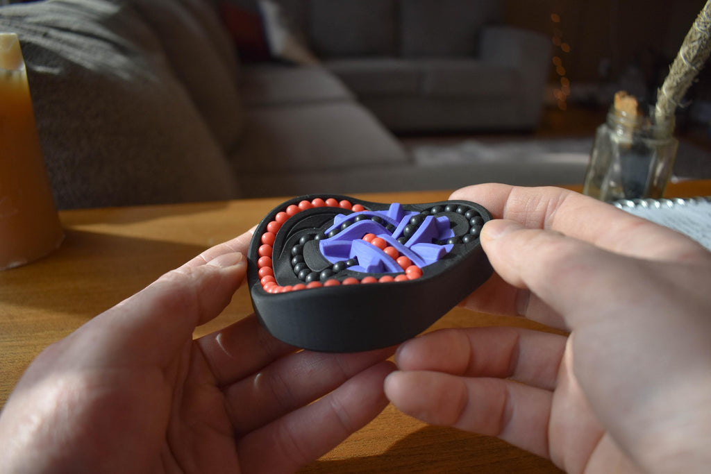 Black and red mechanical puzzle brainteaser held in hands, featuring intricate interlocking pieces for fidget play. - andEleven - The Taurus (2-Color)
