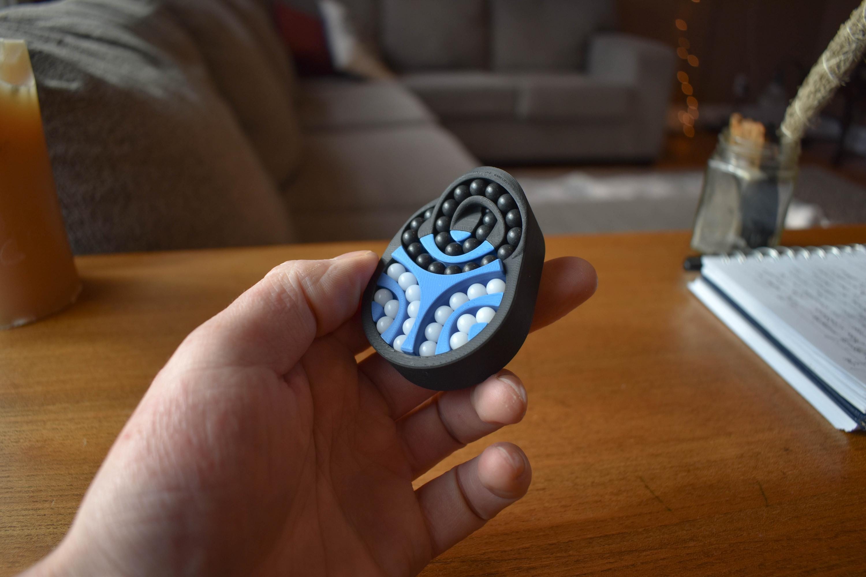 Black and blue spiral mechanical puzzle brainteaser fidget held in hand on wooden table. - andEleven - The Pretzel