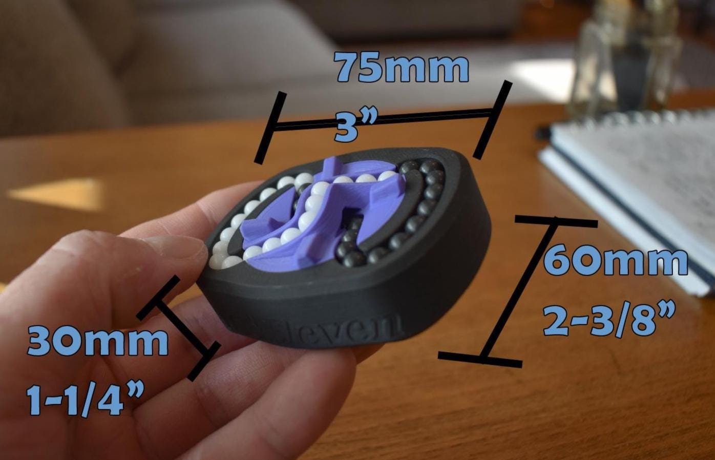 Compact black and purple mechanical puzzle fidget toy with brainteaser design held in hand, 75mm width. - andEleven - The Infinity (2-Color)