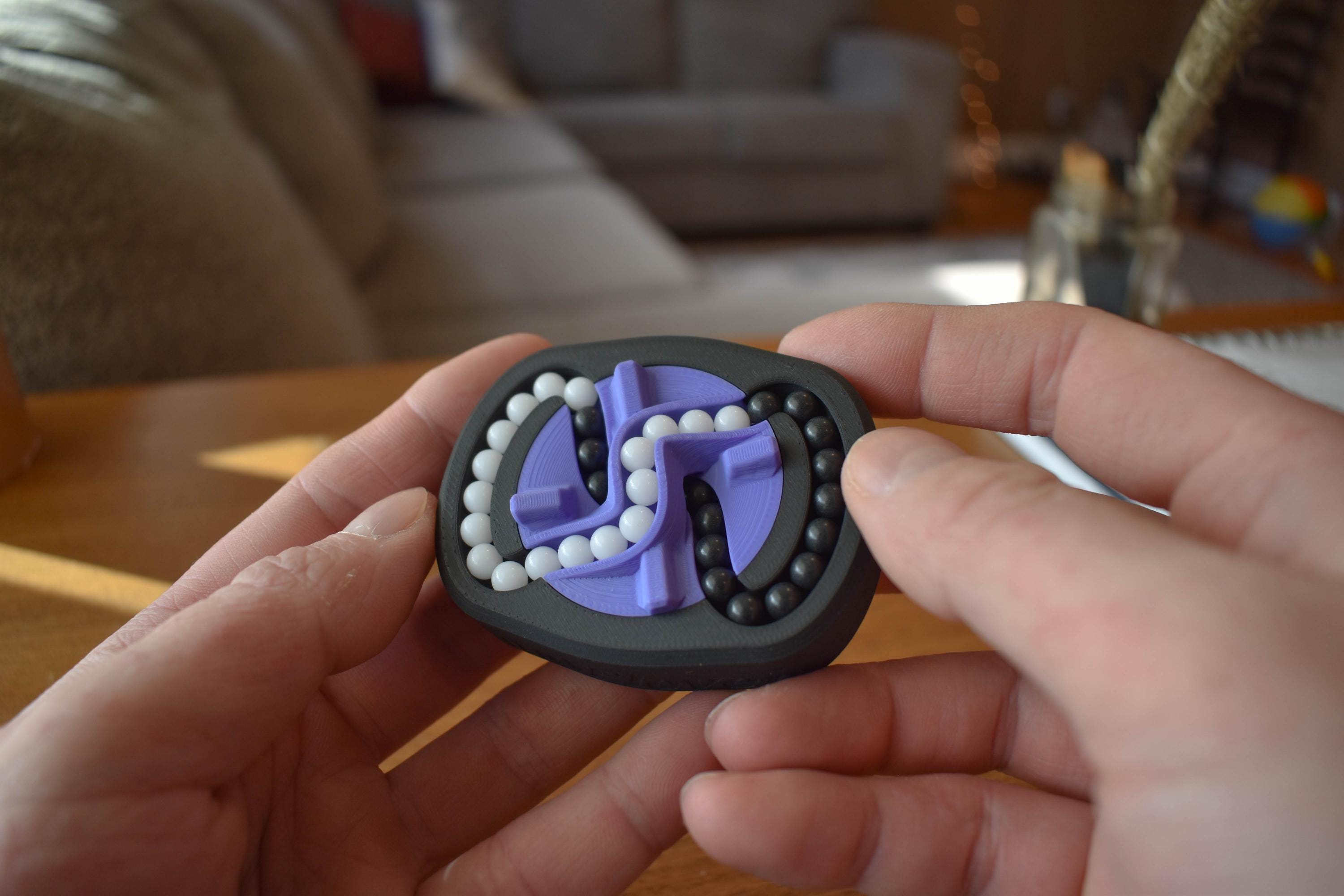 Black and purple mechanical puzzle brainteaser fidget held between hands against blurred background. - andEleven - The Infinity (2-Color)