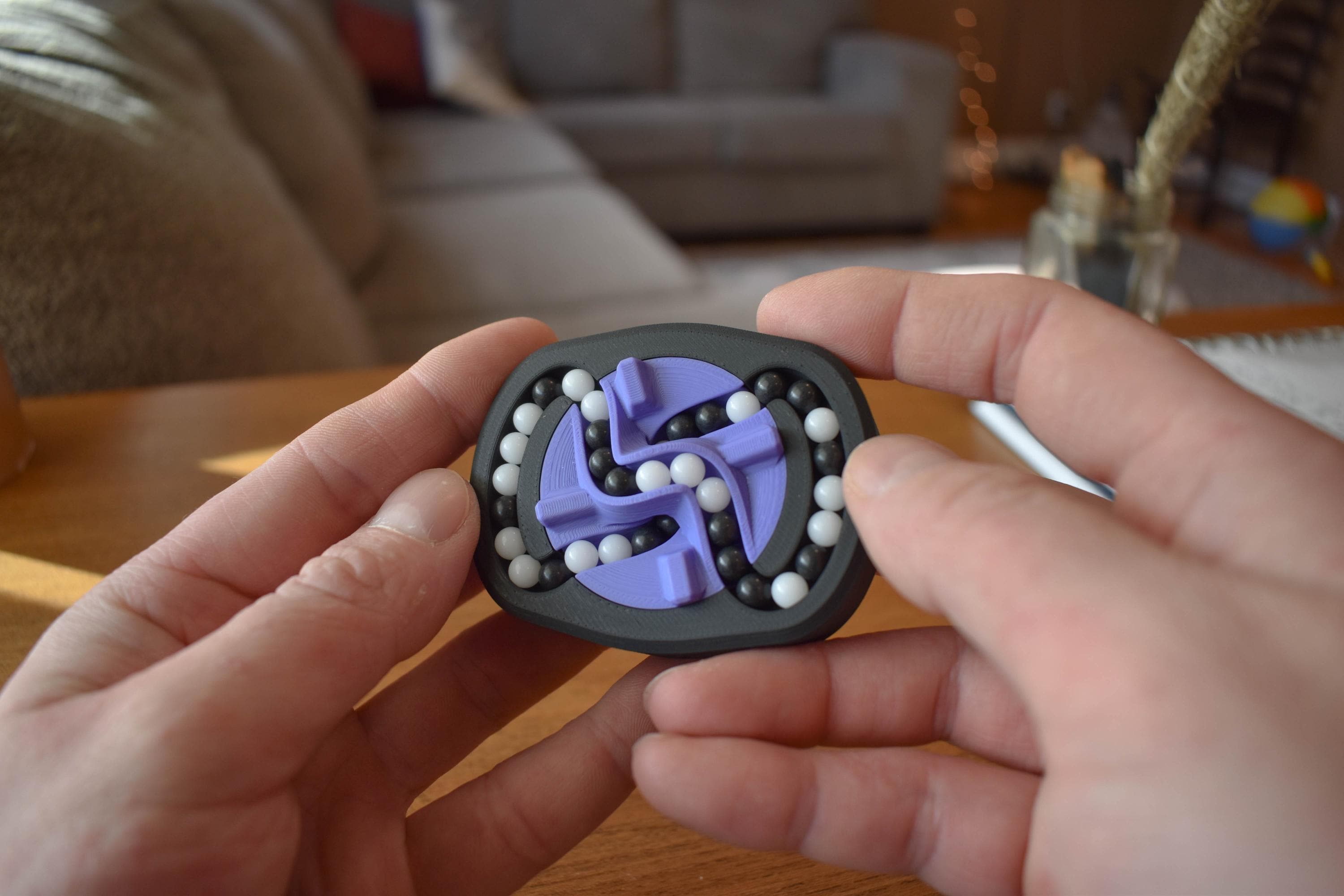 Compact black and purple mechanical puzzle with silver balls, held as a brainteaser fidget toy. - andEleven - The Infinity (2-Color)