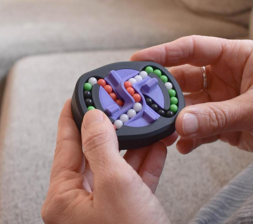 Compact mechanical puzzle with black casing and four colored bead tracks, brainteaser fidget toy held in hands. - andEleven - The Infinity (4-Color)