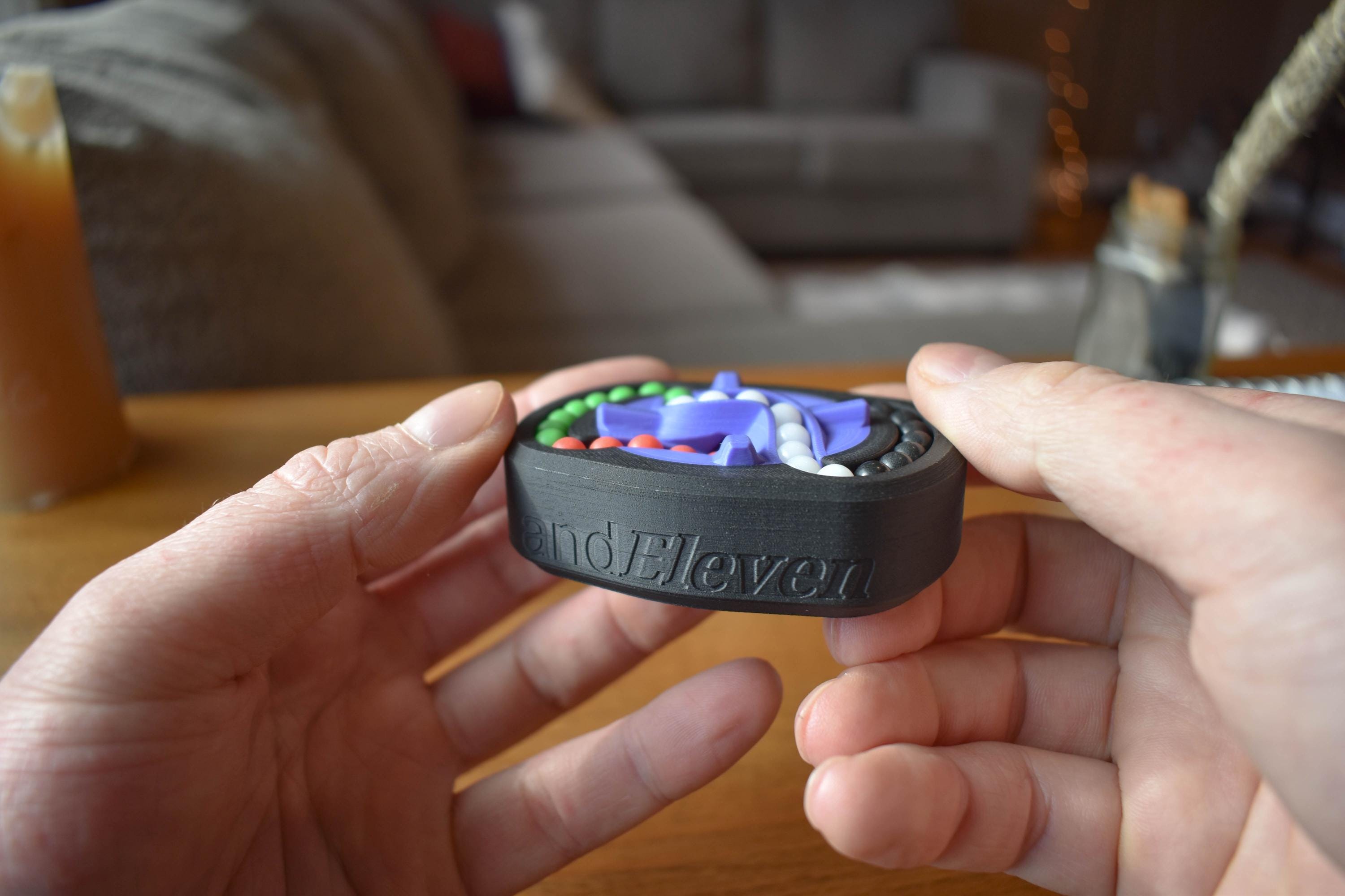 Compact black and gray mechanical puzzle fidget held in hands with colorful interlocking pieces, brainteaser toy. - andEleven - The Infinity (4-Color)