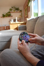 Compact round mechanical puzzle with colorful buttons held as a brainteaser and fidget toy. - andEleven - The Taurus (4-Color)