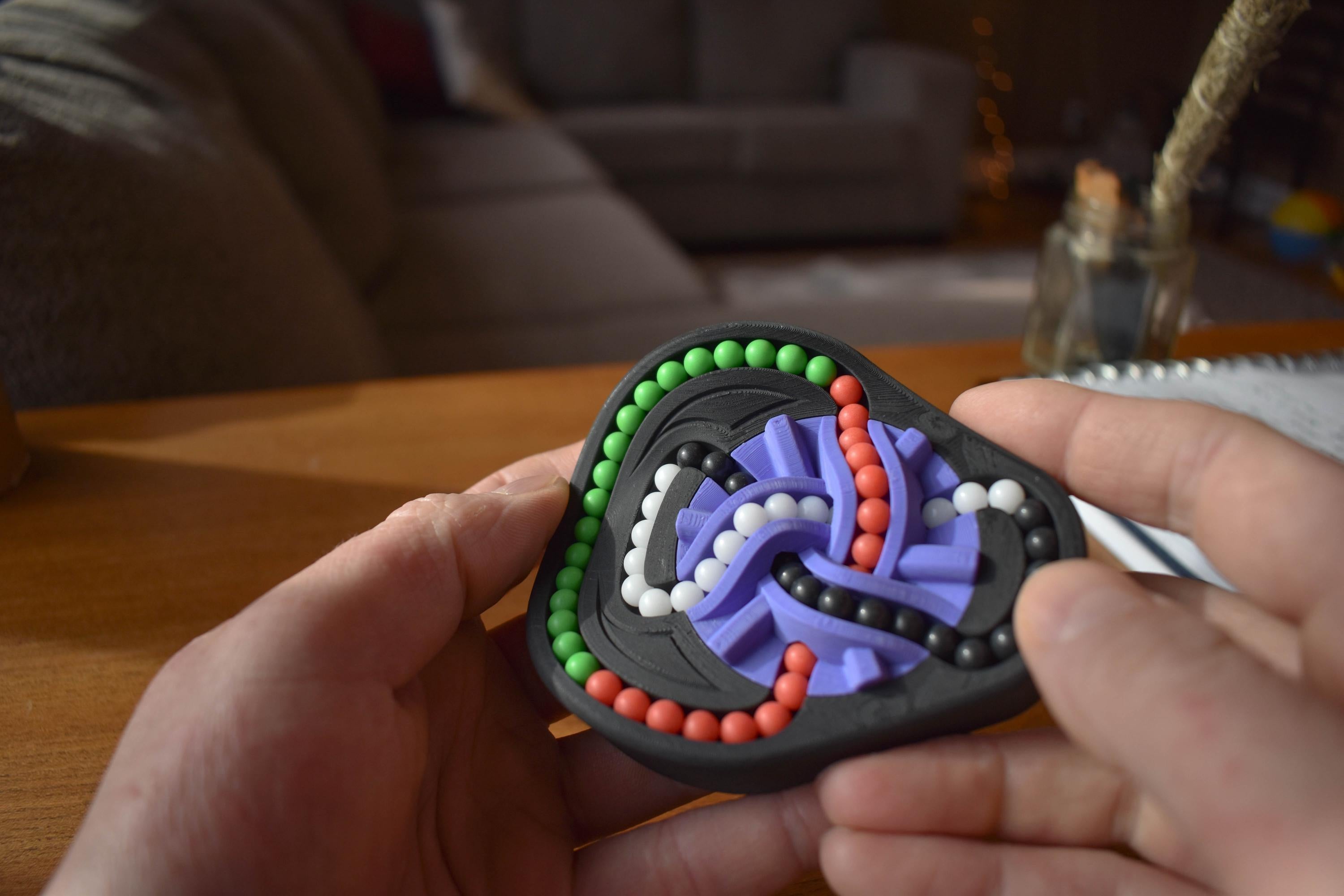 Compact mechanical puzzle with colorful interconnected tracks and beads, a fidget brainteaser toy. - andEleven - The Taurus (4-Color)