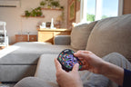 Hands holding The Taurus 4-color mechanical puzzle brainteaser with fidget elements on a couch. - andEleven - The Taurus (4-Color)