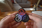 Triad mechanical puzzle brainteaser fidget with colorful ball bearings held in hands on wooden table. - andEleven - The Triad