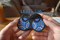Two-color black and blue mechanical puzzle brainteaser fidget held in hands against blurred background. - andEleven - The Figure-Eight (2-Color)