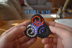 Triangular mechanical puzzle with three interconnected colored tracks and small beads, a brainteaser fidget toy held by. - andEleven - The Triad