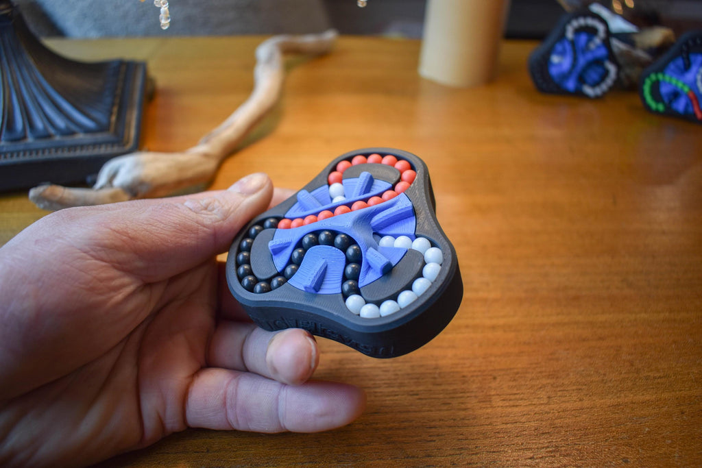 Handheld 3-color mechanical puzzle brainteaser fidget with blue, orange, and white beads on black frame. - andEleven - The Delta (3-Color)