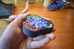 Hand holding a black mechanical puzzle brainteaser with four colorful sections and small beads, fidget toy. - andEleven - The Delta (4-Color)
