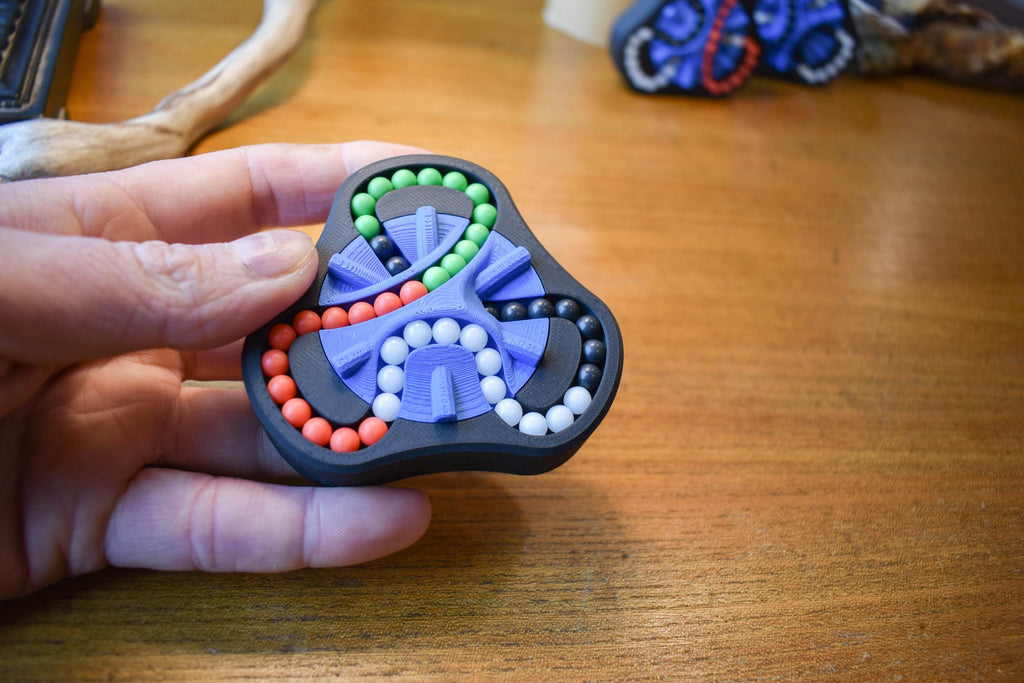 Small hand-held mechanical puzzle with four colors and bead sliders, a brainteaser fidget toy. - andEleven - The Delta (4-Color)