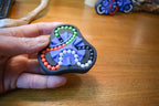 Small hand-held mechanical puzzle with four colors and bead sliders, a brainteaser fidget toy. - andEleven - The Delta (4-Color)