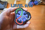 Compact triangular mechanical puzzle with four colored bead tracks, designed as brainteaser fidget toy. - andEleven - The Delta (4-Color)