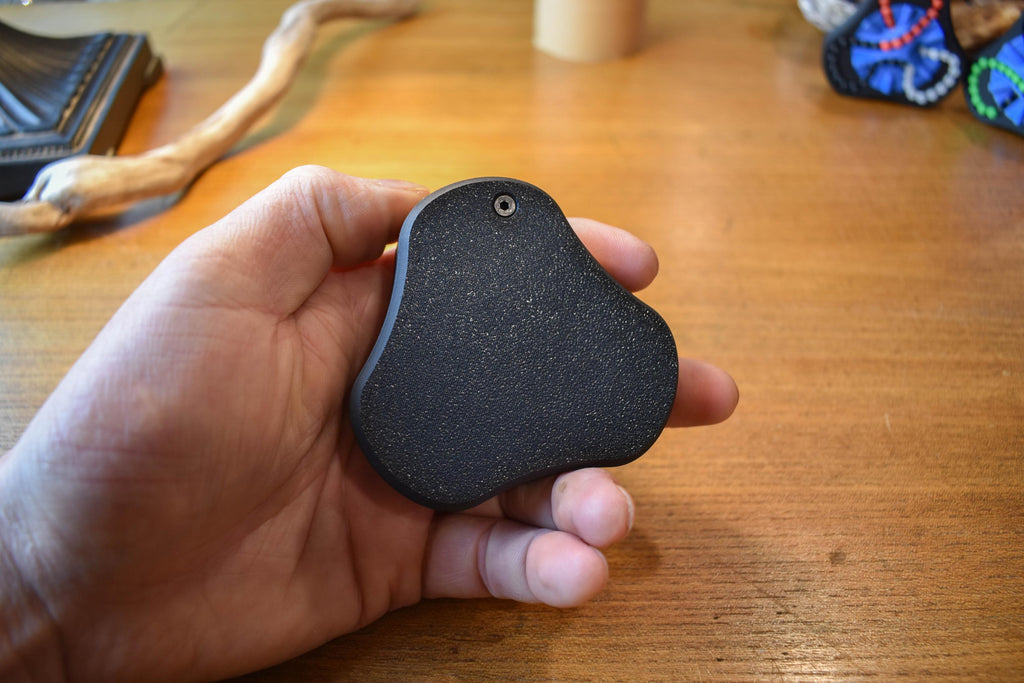 Compact black mechanical puzzle with smooth edges held in hand, designed as a fidget brainteaser. - andEleven - The Delta (2-Color)