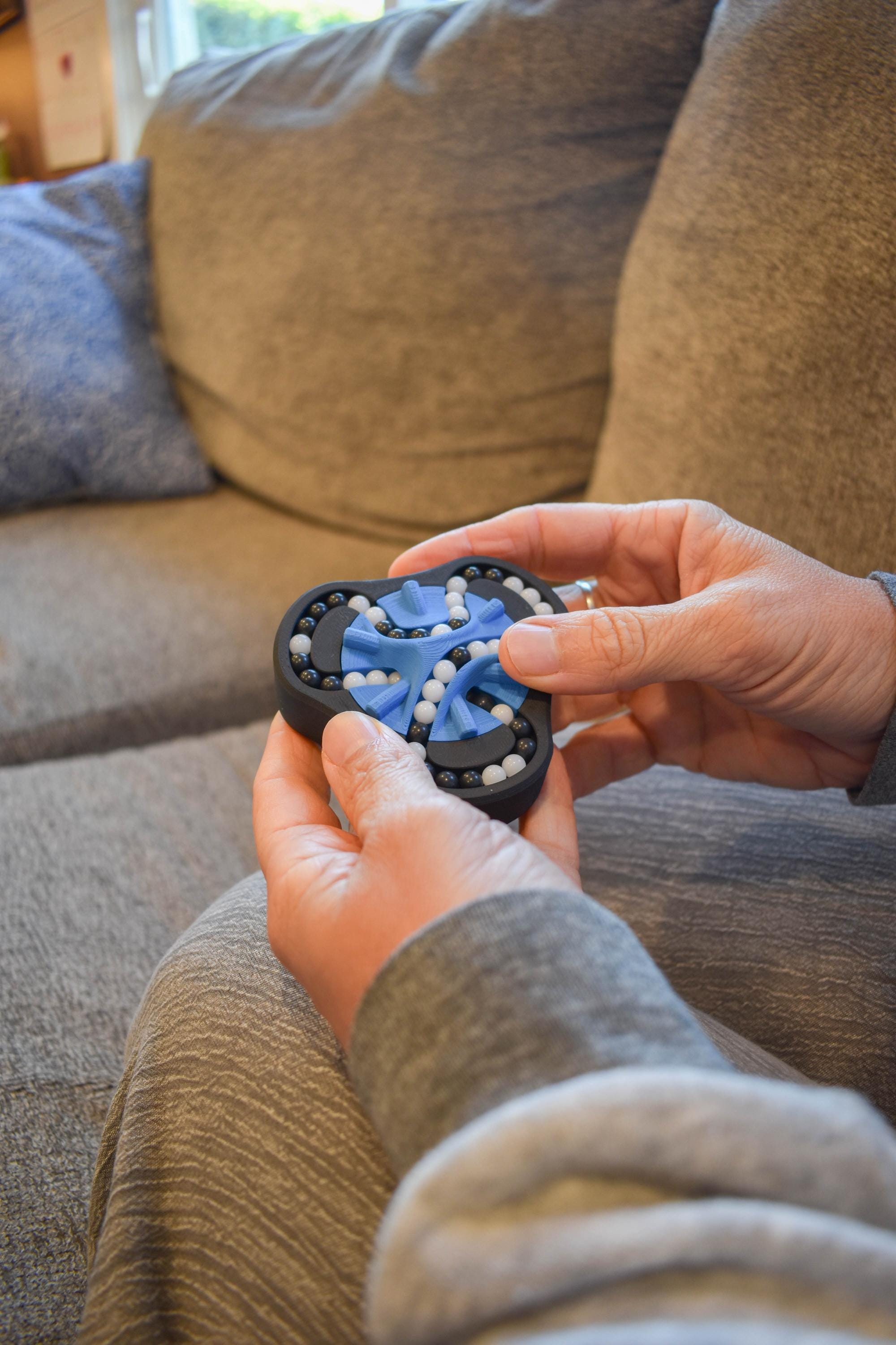 Black and blue two-color mechanical puzzle held in hands, designed as a brainteaser and fidget toy. - andEleven - The Delta (2-Color)