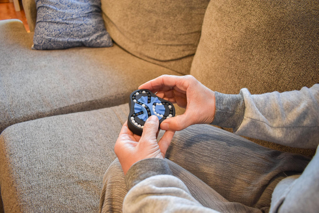 Hands holding black and blue geometric mechanical puzzle brainteaser fidget on a couch. - andEleven - The Delta (2-Color)