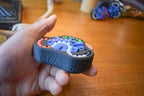 Compact black mechanical puzzle with colorful interlocking pieces held in hand, brainteaser and fidget toy. - andEleven - The Delta (4-Color)