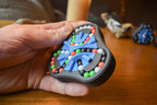 Hand holding black triangular mechanical puzzle with blue, red, green, and white beads, brainteaser fidget toy. - andEleven - The Delta (4-Color)