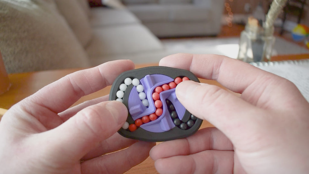 A person trying to solve the product by cycling the balls through the tracks, and turning the center rotor. The rotor makes a satisfying snap is it clicks in to place.