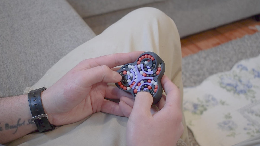 A person trying to solve the product by cycling the balls through the tracks, and turning the center rotor. The rotor makes a satisfying snap is it clicks in to place.