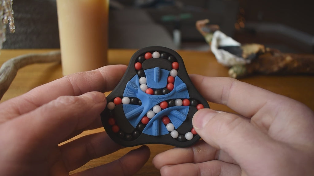 A person trying to solve the product by cycling the balls through the tracks, and turning the center rotor. The rotor makes a satisfying snap is it clicks in to place.